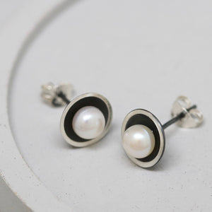 Pair of sterling silver black pearl earrings on a grey dish displayed from above to show the Art Deco inspired design