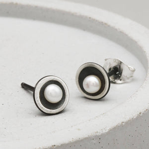 Small black pearl stud earrings in oxidised sterling silver with an elegant Art Deco-inspired domed design.