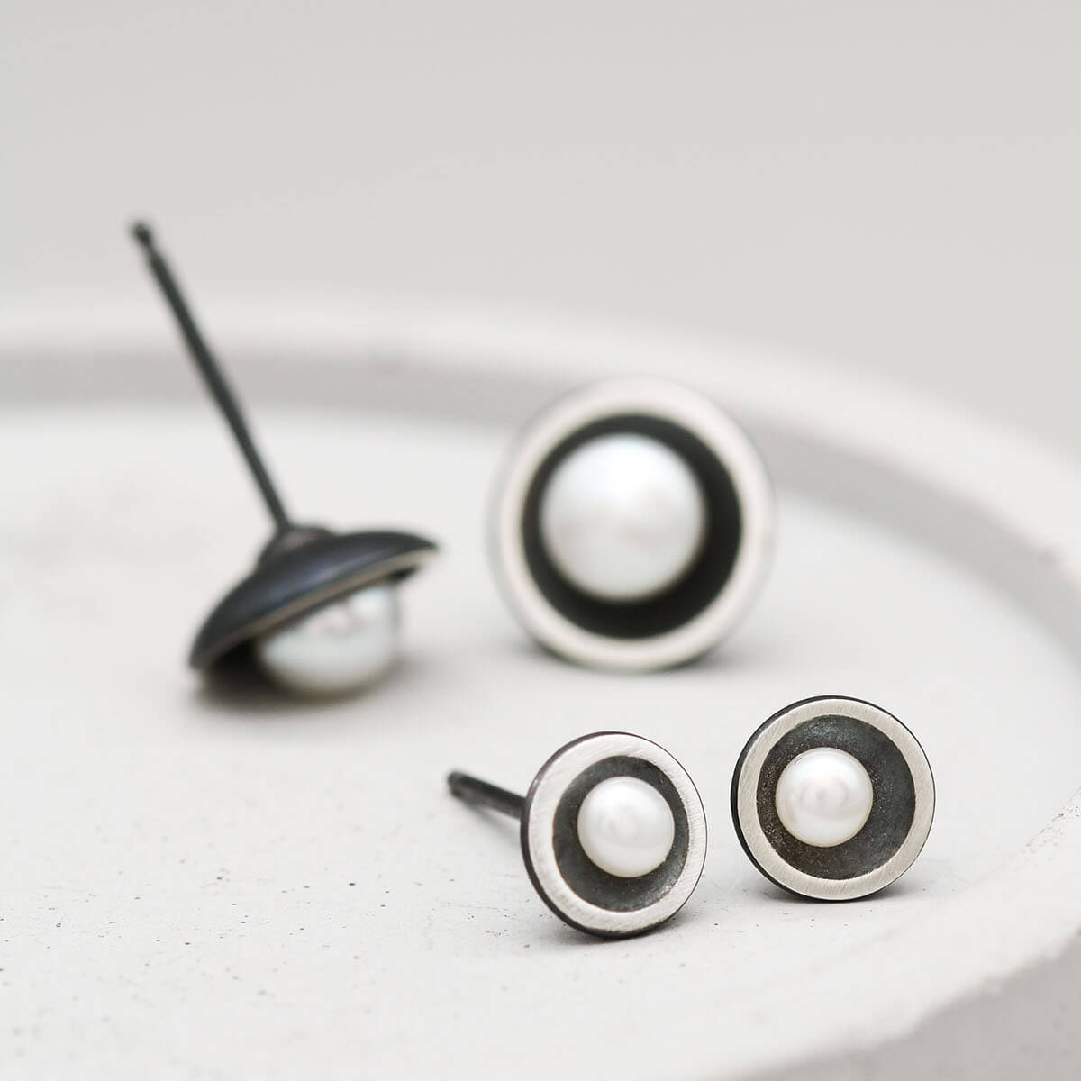 Petite and Classic black pearl stud earrings shown side by side to compare the two sizes.