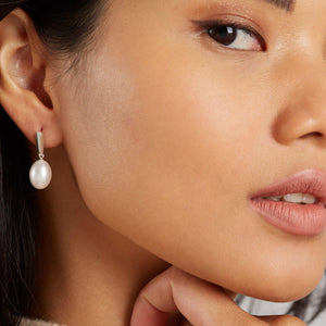 Lifestyle shot of the earrings worn, highlighting how the sculptural silver detail enhances the natural pearl glow.