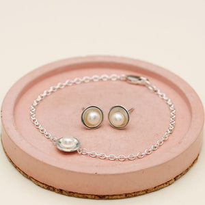 Sterling silver pearl bracelet displayed with matching handmade pearl stud earrings featuring genuine freshwater pearls.