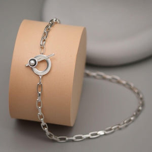 Handmade chunky pearl necklace in sterling silver featuring a bold rectangular trace chain, T-bar toggle clasp and genuine freshwater pearl on a pink display with grey background.