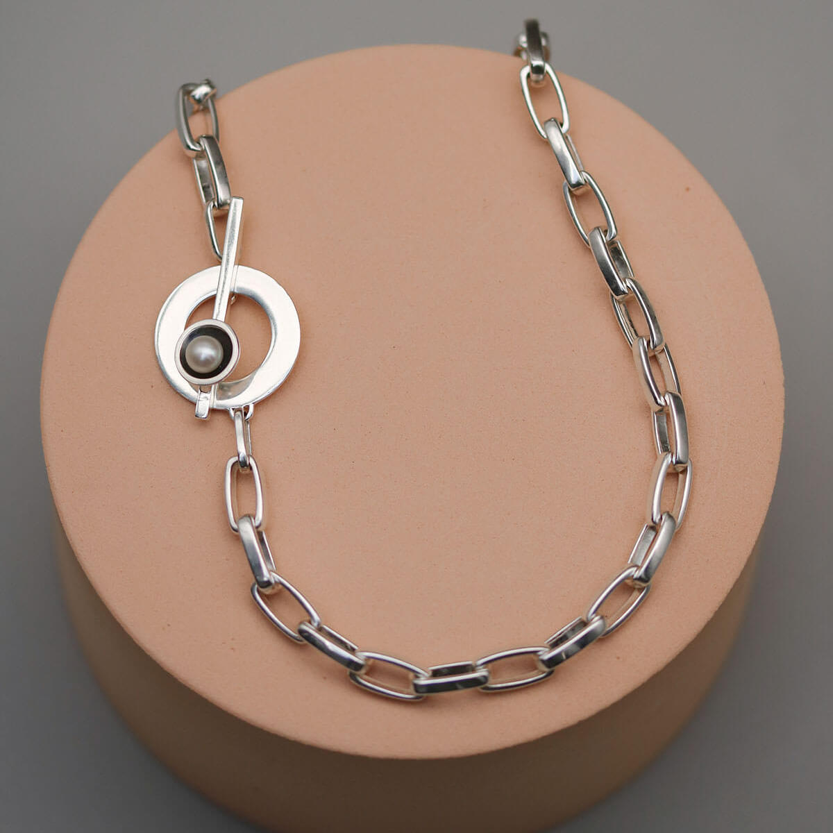 Close up of a handmade sterling silver pearl chain necklace showing the contemporary toggle clasp, chunky rectangular chain links and genuine freshwater pearl.