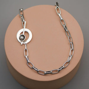 Close up of a handmade sterling silver pearl chain necklace showing the contemporary toggle clasp, chunky rectangular chain links and genuine freshwater pearl.