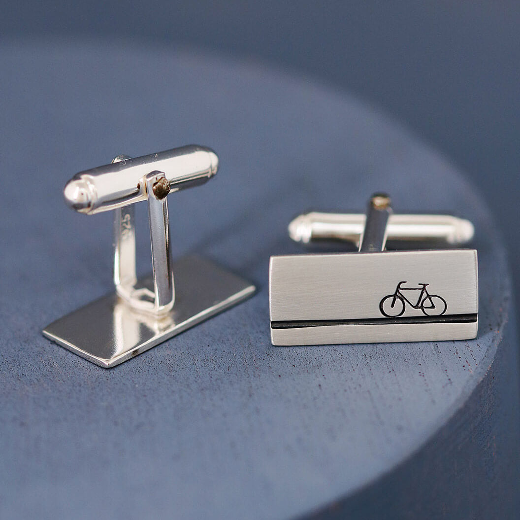 Close-up of sterling silver cycling cufflinks on a deep blue background, handmade gift for bicycle lovers and ideal Father’s Day present for a cycling dad.