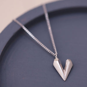 Heart shaped necklace on a blue dish featuring a faceted sterling silver heart charm on an 18 inch chain, a dainty heart necklace gift for her