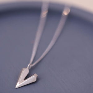Heart shaped necklace photographed on a blue dish showing the faceted silver heart charm and delicate diamond cut curb chain
