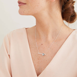 Oxidised sterling silver geometric pearl necklace worn with a dark outfit, featuring a genuine freshwater pearl and horizontal bar pendant.