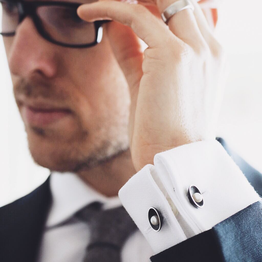 Black double-sided pearl cufflinks worn on a white dress shirt, showing pearls on both sides of the cuff.