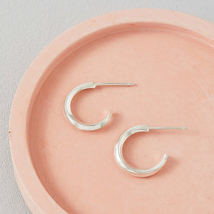 Small silver hoop stud earrings on a pink dish, timeless sterling silver hoop earrings for women gift idea