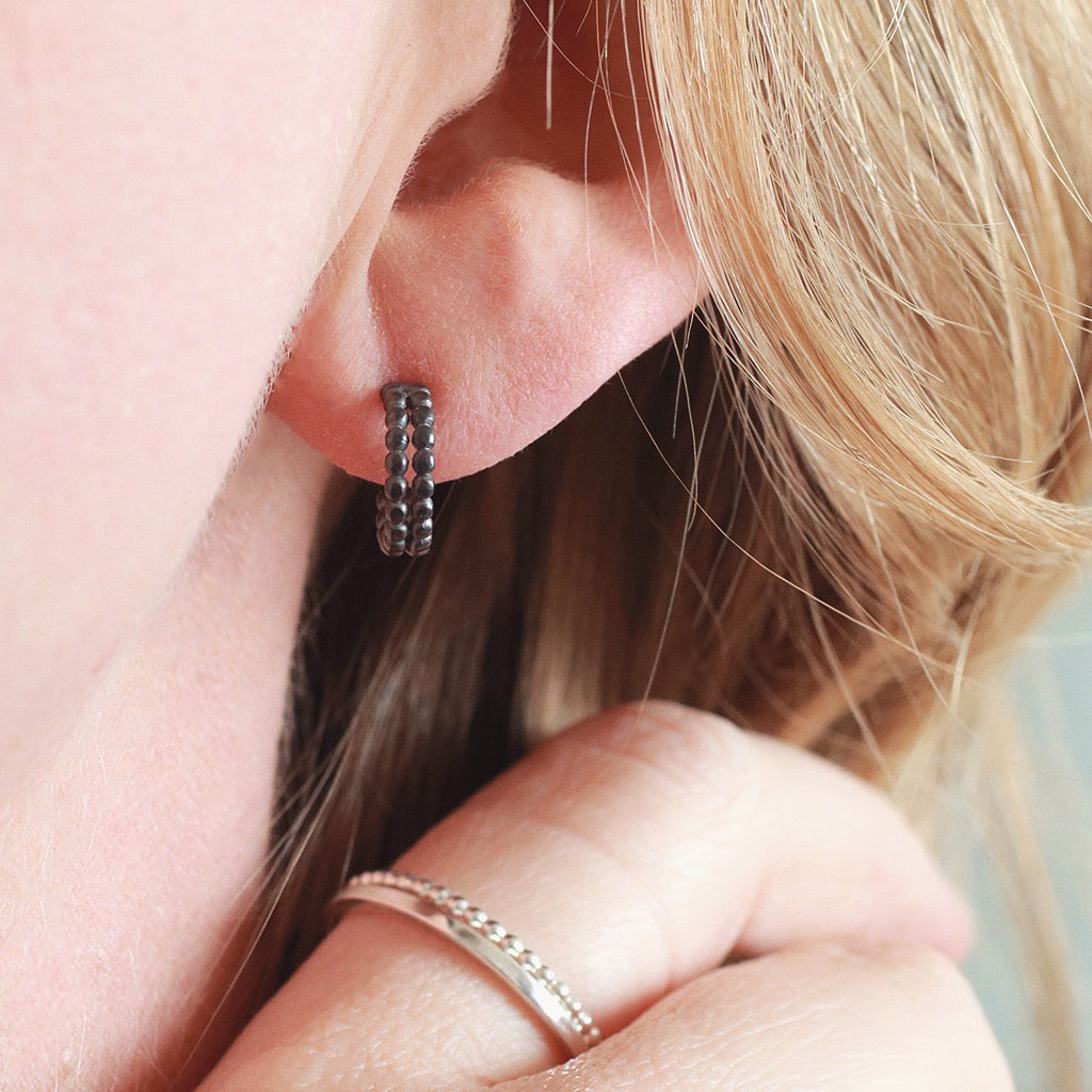Black hoop earrings for women modelled in second piercing, small black hoop earrings close up