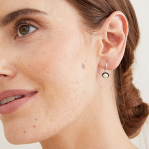 Model wearing handmade black pearl drop earrings in oxidised sterling silver with genuine freshwater pearls. 