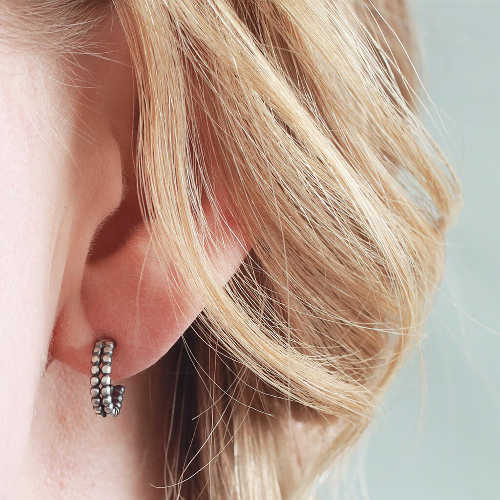 Little black hoop earrings modelled in second piercing, silver and black hoop earrings close up