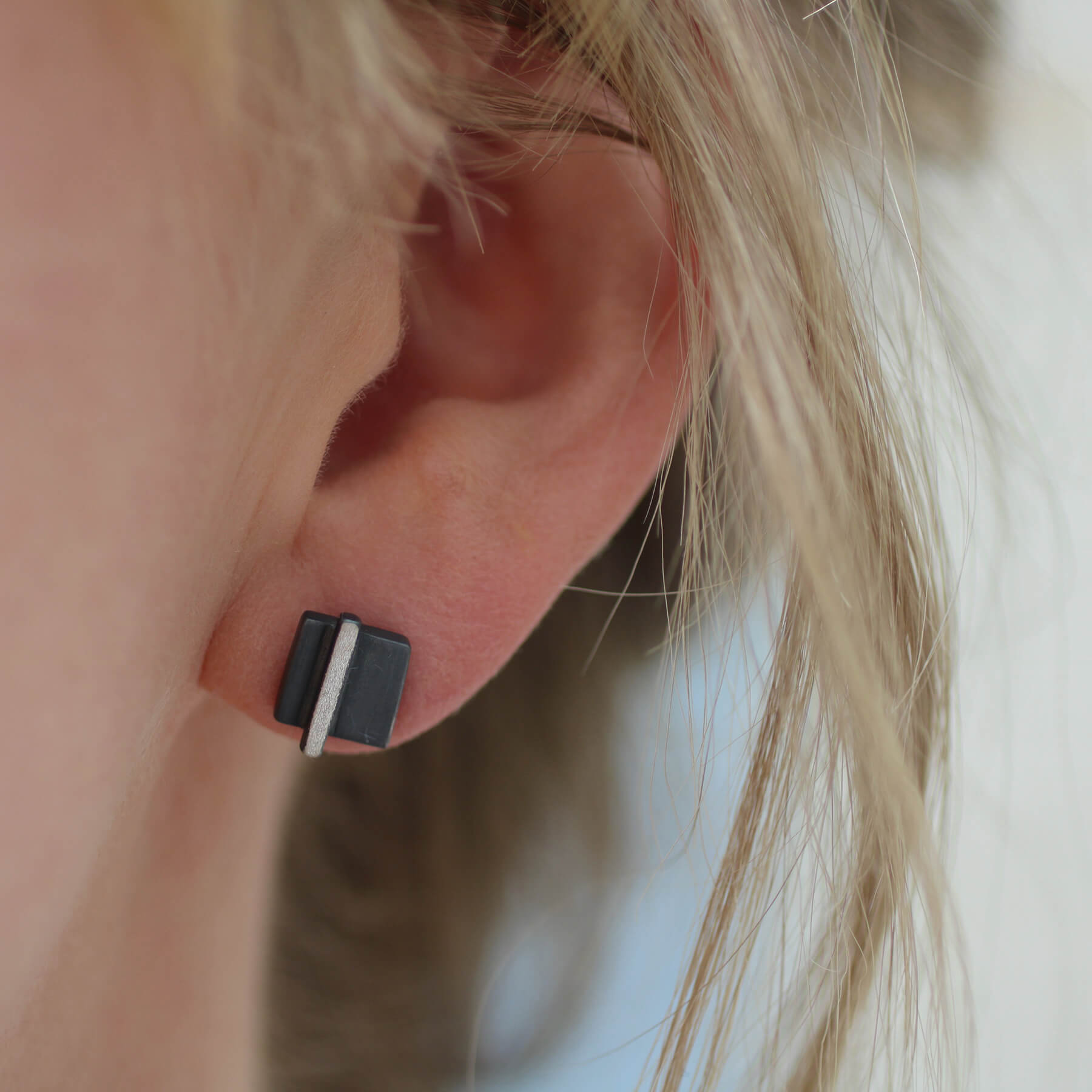Model wearing silver and black earrings showing size and fit, modern gift for her for birthdays or anniversaries.