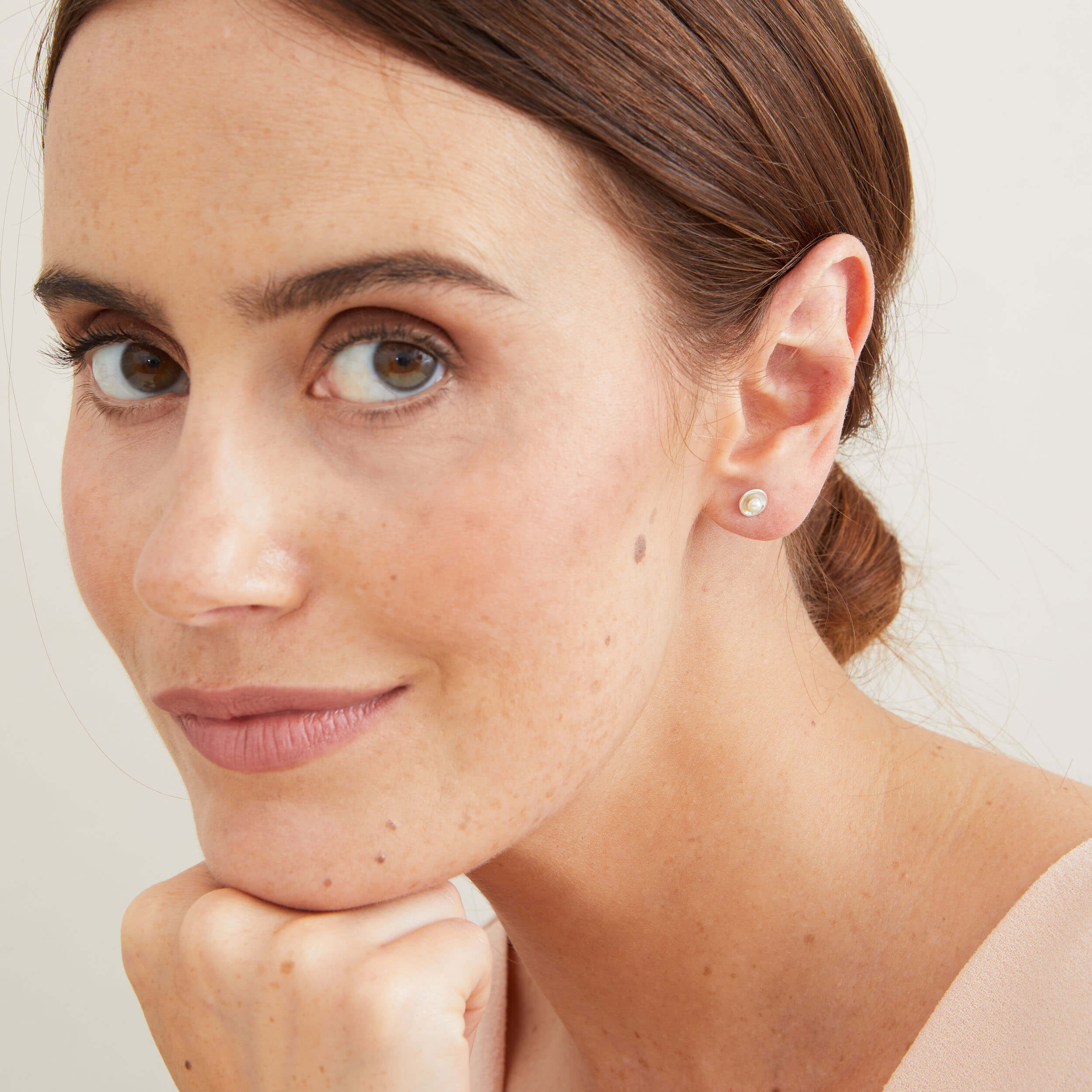 Petite freshwater pearl stud earrings modelled to show their subtle size