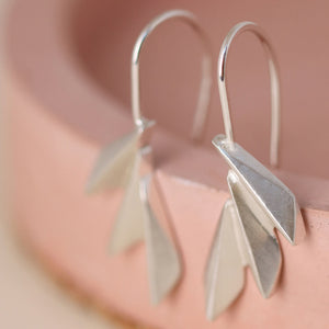 Silver art deco drop earrings styled on a pink dish with clean angular fan lines; ideal fan drop earrings for special occasion gifting.