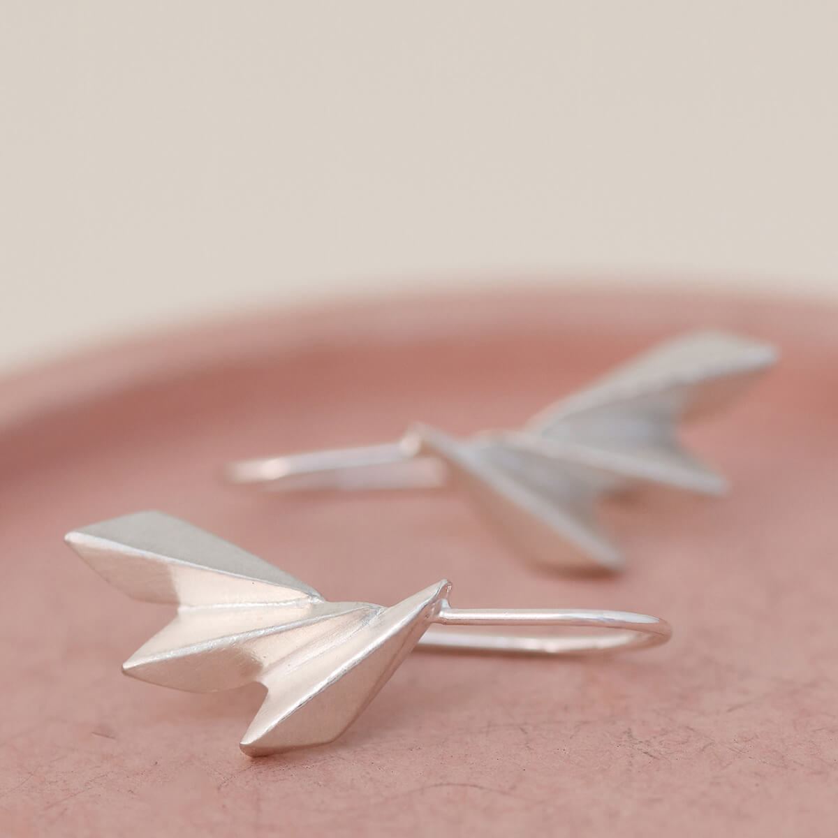 Detailed shot of fan drop earrings on a pink dish showing the sculpted ridges; beautiful gift for birthdays, graduations or just because.