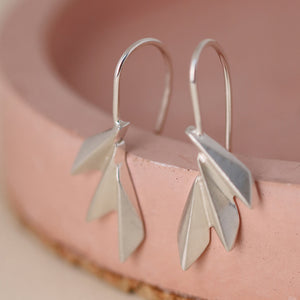 Geometric fan drop earrings photographed on a pink dish, showcasing the matte silver finish; perfect Christmas gift for lovers of art deco jewellery.