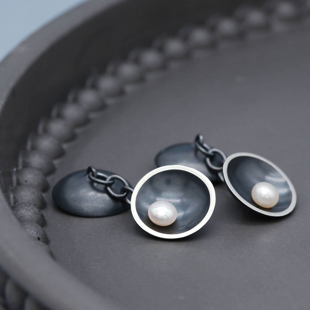 Handmade black sterling silver cufflinks featuring freshwater pearls on both ends of the cufflink design.
