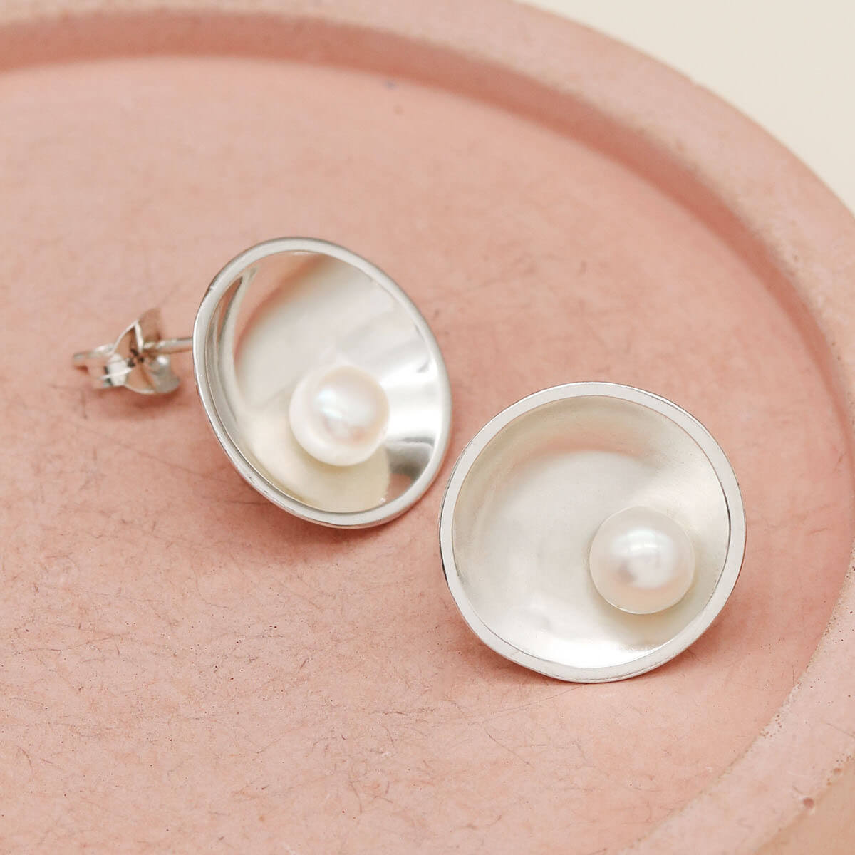 Close-up of Signature sterling silver pearl earrings featuring polished domed settings and genuine freshwater pearls.