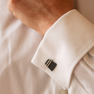 Close-up of black cufflinks fastened on a white shirt cuff sleeve. A sleek and understated detail, making an ideal birthday gift idea for husband or stylish groom accessory.