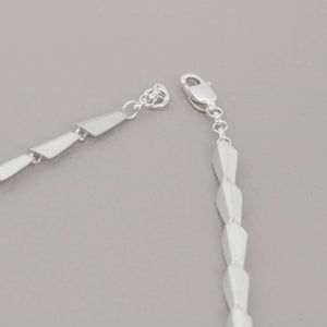 Close-up of the clasp detail on the silver link necklace worn with a V-neck dress — a contemporary necklace with elegant finishing touches.