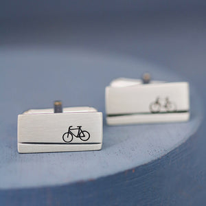 Detailed shot of bicycle design on sterling silver cycling cufflinks, photographed on deep blue background, a unique Christmas gift for a cycling husband.