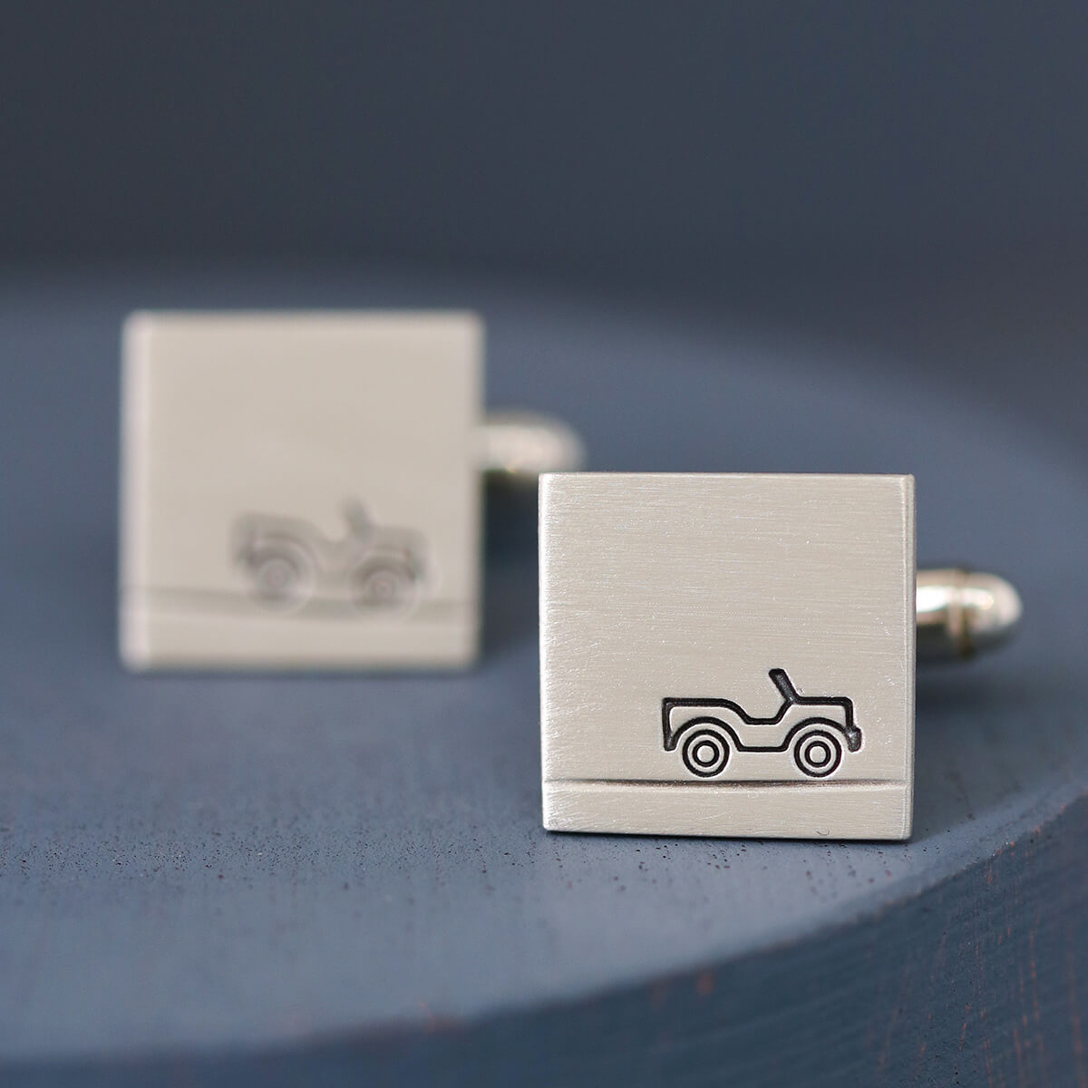 Side view of Car cufflinks on deep blue background showing matte silver texture, a stylish and understated gift for car lovers.