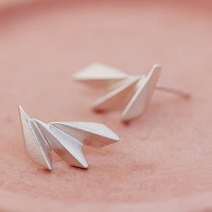 Art deco silver earrings photographed on a pink dish for a detailed view of the texture.