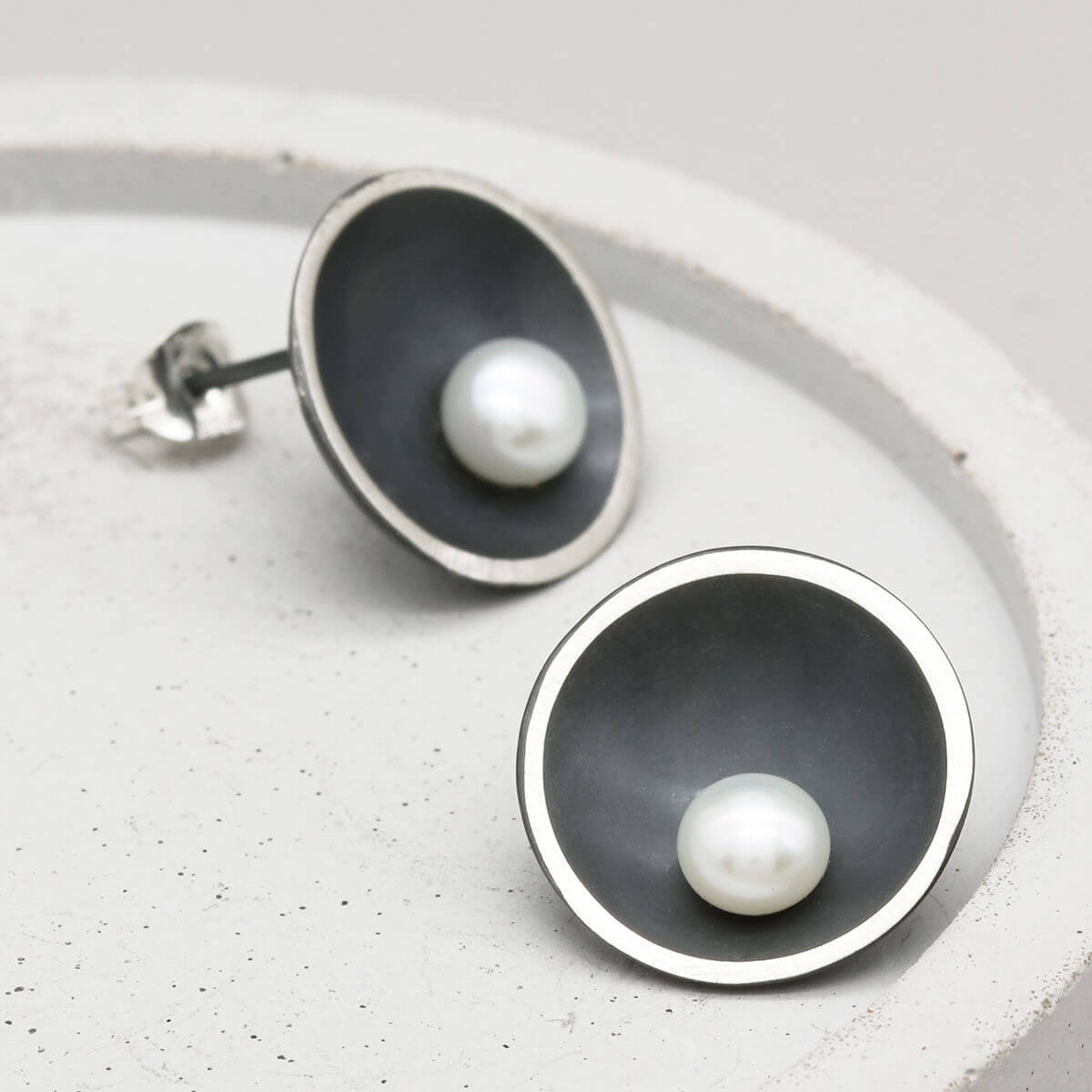 Contemporary black pearl stud earrings handcrafted in oxidised sterling silver with an Art Deco-inspired domed design.
