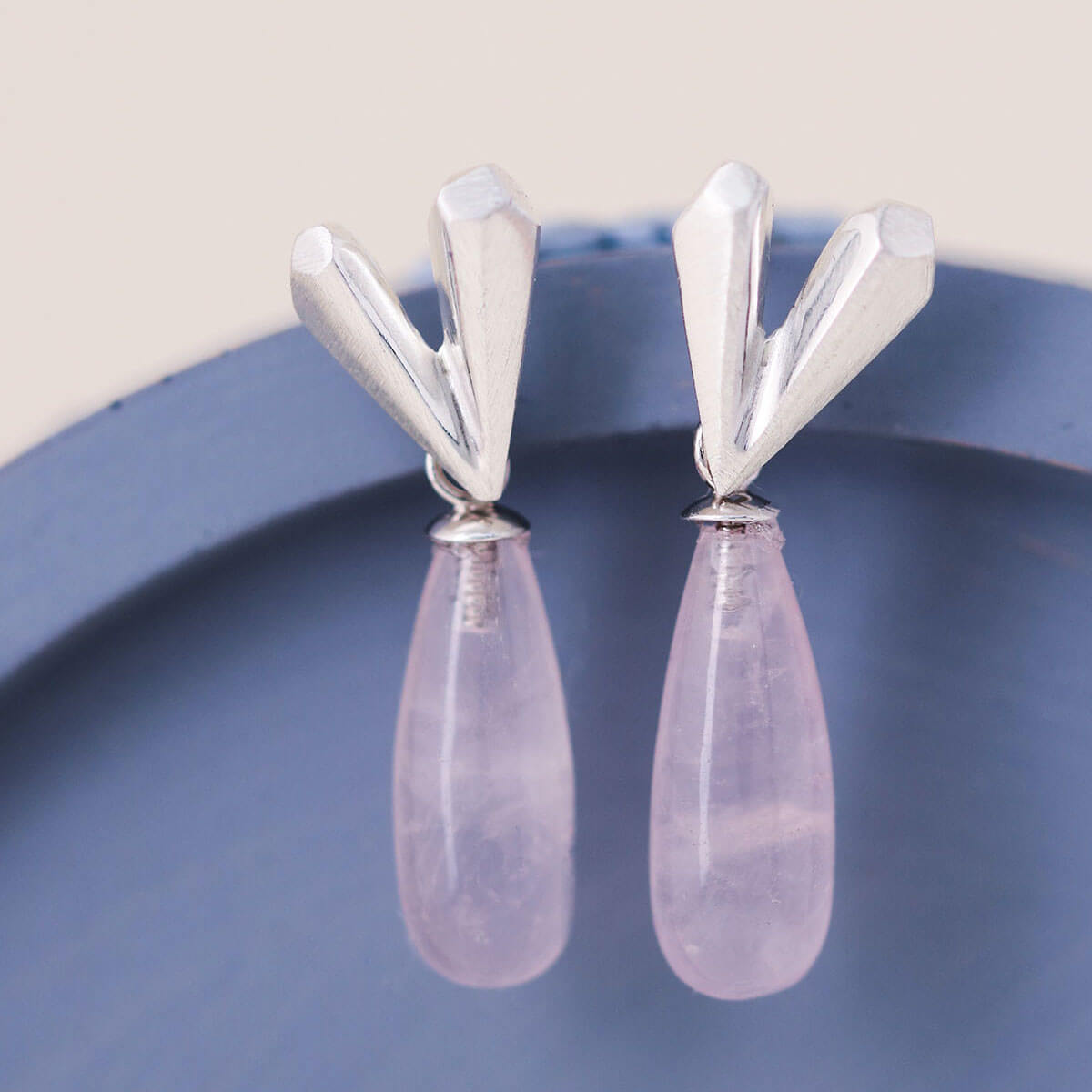 Heart dangle earrings with faceted sterling silver heart and rose quartz drop displayed on a blue dish, Pink heart earrings handmade in silver
