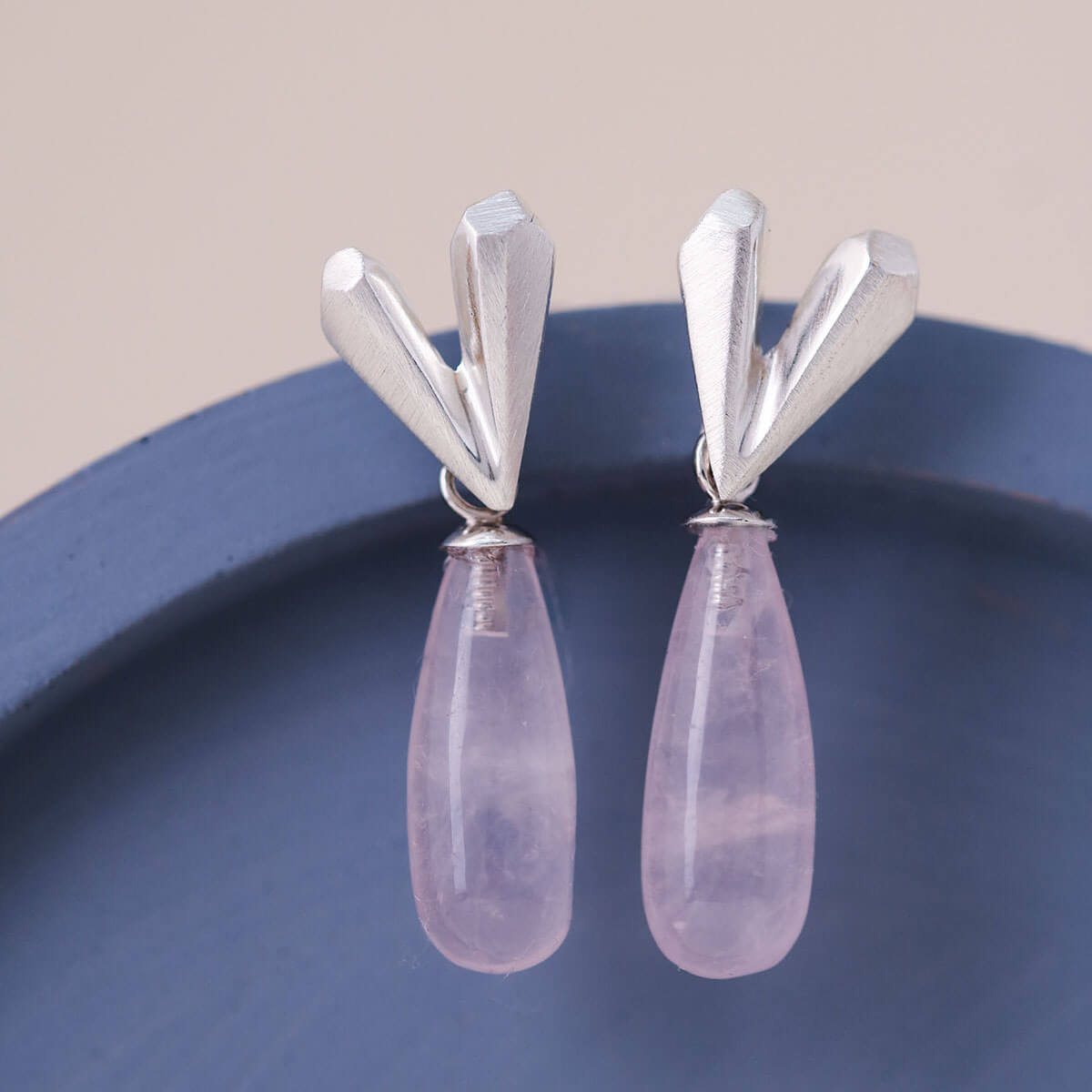 Handmade heart dangle earrings in sterling silver with rose quartz drop, Pink heart earrings photographed on a blue ceramic dish