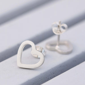 Polished heart shaped silver earrings on grey dish, handcrafted sterling silver studs