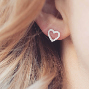 Matte heart sterling silver earrings being worn in ear