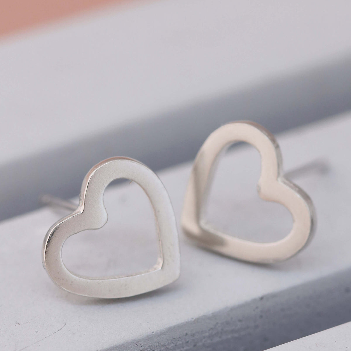 Polished heart sterling silver earrings on grey dish, classic heart shaped silver earrings