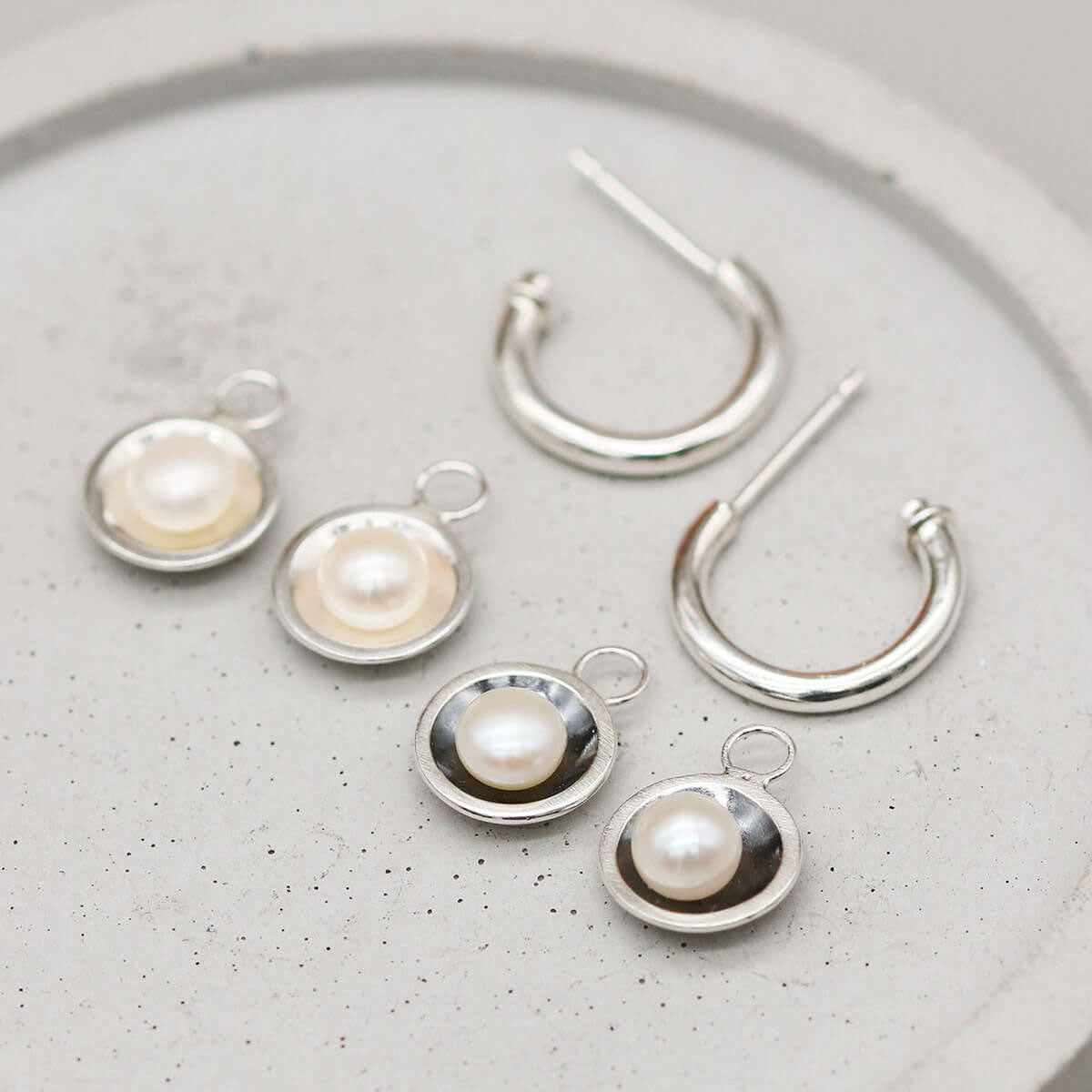 Sterling silver hoop earrings shown with polished silver and oxidised black interchangeable freshwater pearl charms.
