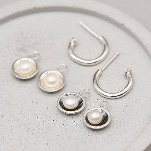 Sterling silver hoop earrings shown with polished silver and oxidised black interchangeable freshwater pearl charms.