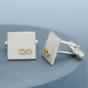 Gold and silver Cufflinks personalised, shown side by side on a deep blue background highlighting the geometric square shape and smooth finish.