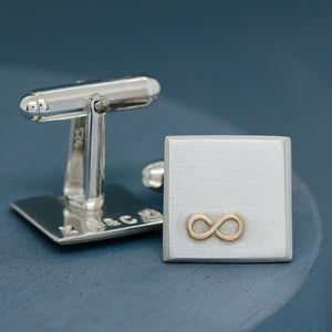 One cufflink upturned to show hand-stamped letters on the reverse, with the other face on displaying the gold infinity symbol – Cufflinks personalised with hidden meaning.