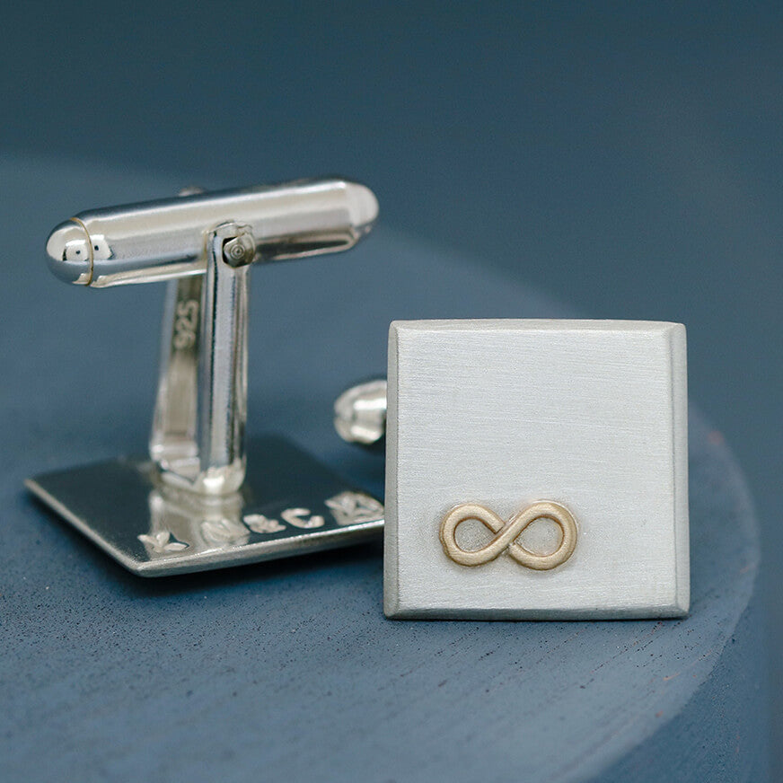 One cufflink upturned to show hand-stamped letters on the reverse, with the other face on displaying the gold infinity symbol – Cufflinks personalised with hidden meaning.