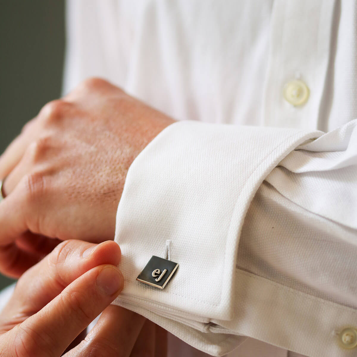 Model wearing mens cufflinks personalised with monogram initials, classic silver cufflinks with initials for formal occasions.