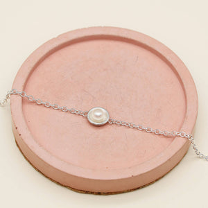 Ladies pearl bracelet handcrafted in solid sterling silver with a genuine freshwater pearl on a pink dish.