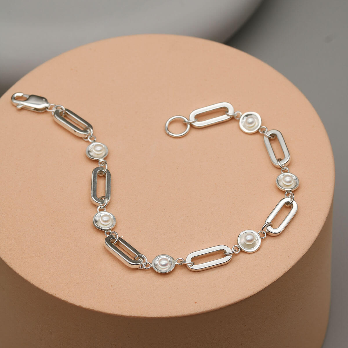 Chunky pearl bracelet showcasing bold sterling silver rectangular links and genuine freshwater pearls on a pink plinth.