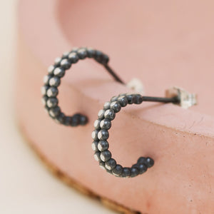 Silver and black hoop earrings arranged on a pink dish, modern small hoop earrings