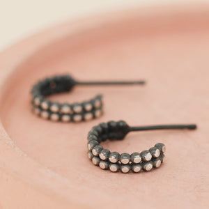 Silver and black hoop earrings photographed on a pink dish, little black hoop earrings for women