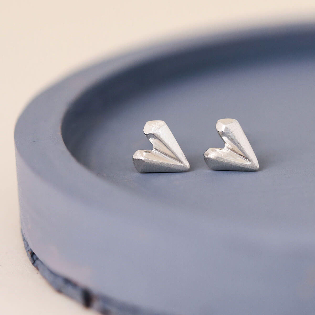 Love heart earrings in sterling silver displayed on a blue dish, dainty silver heart stud earrings ideal gift for her
