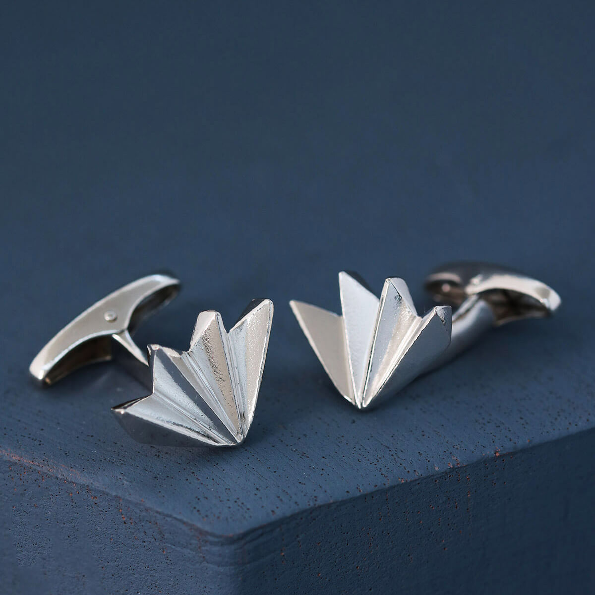 Handcrafted sterling silver art deco cufflinks on deep blue background, timeless men’s cufflinks for weddings or special occasions