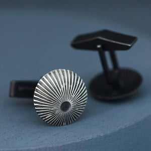Silver and black cufflinks photographed flat on deep blue surface, perfect luxury wedding cufflinks for groom or cycling of formal events.