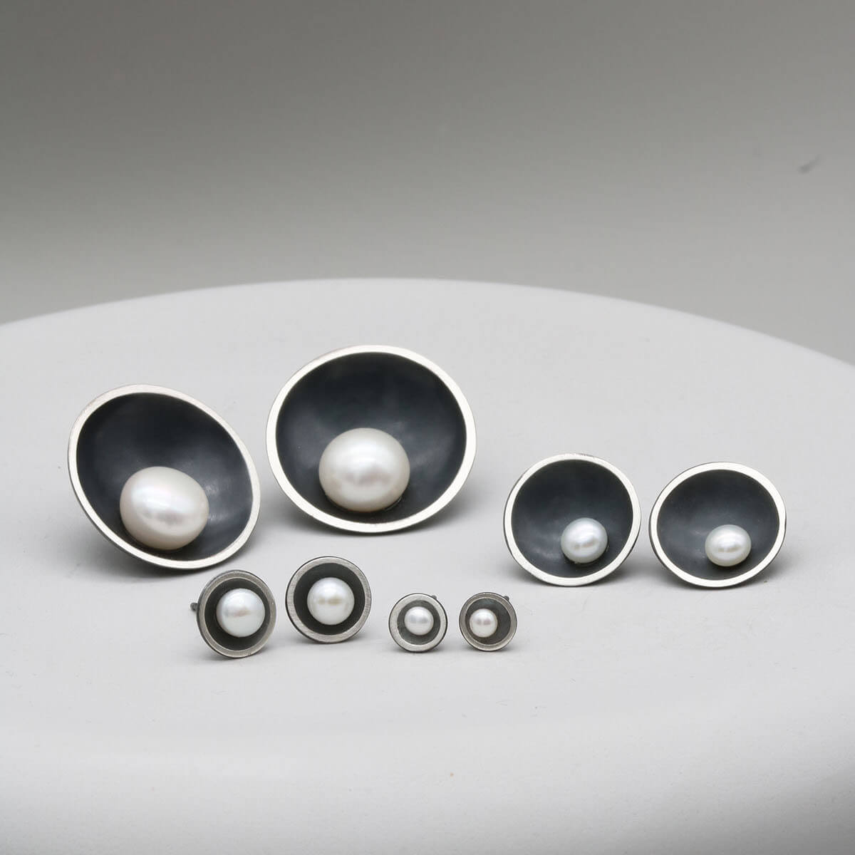Comparison of Petite, Classic, Signature and Statement black pearl stud earrings showing all four sizes side by side.