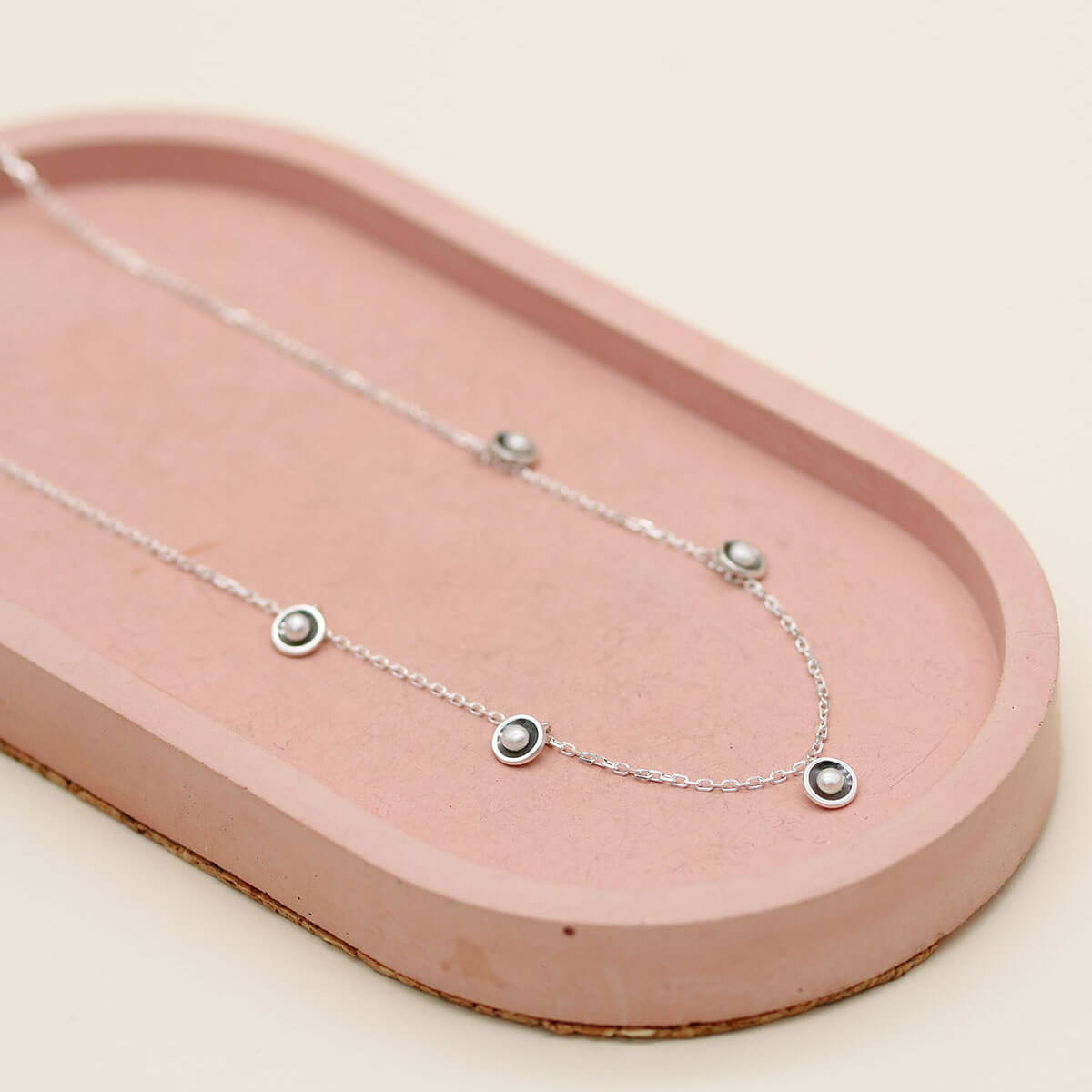 Handmade black pearl chain necklace with five genuine freshwater pearls in oxidised sterling silver displayed on a pink ceramic dish.